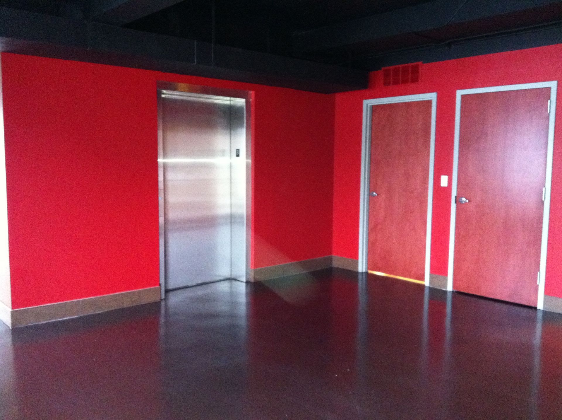 an elevator in a room with red walls and wooden doors