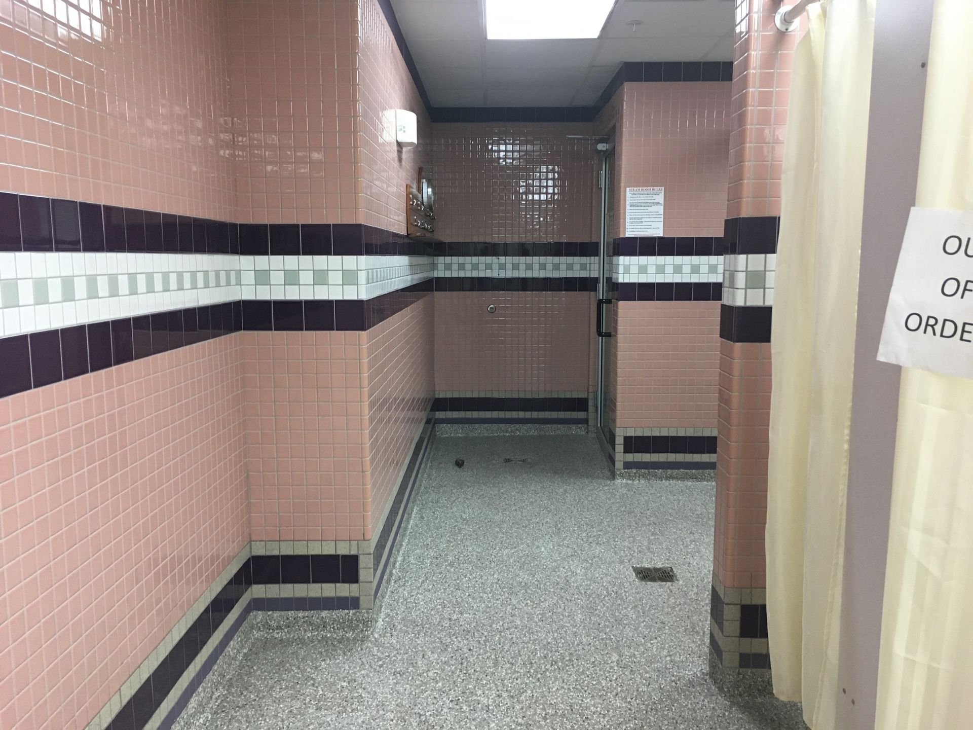 a hallway with pink and purple tiles and a sign that says out of order