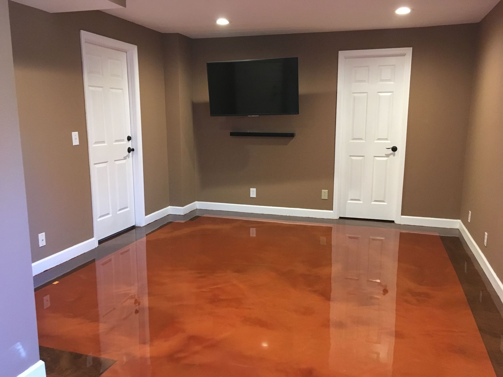 a basement with a metallic floor and a flat screen tv on the wall