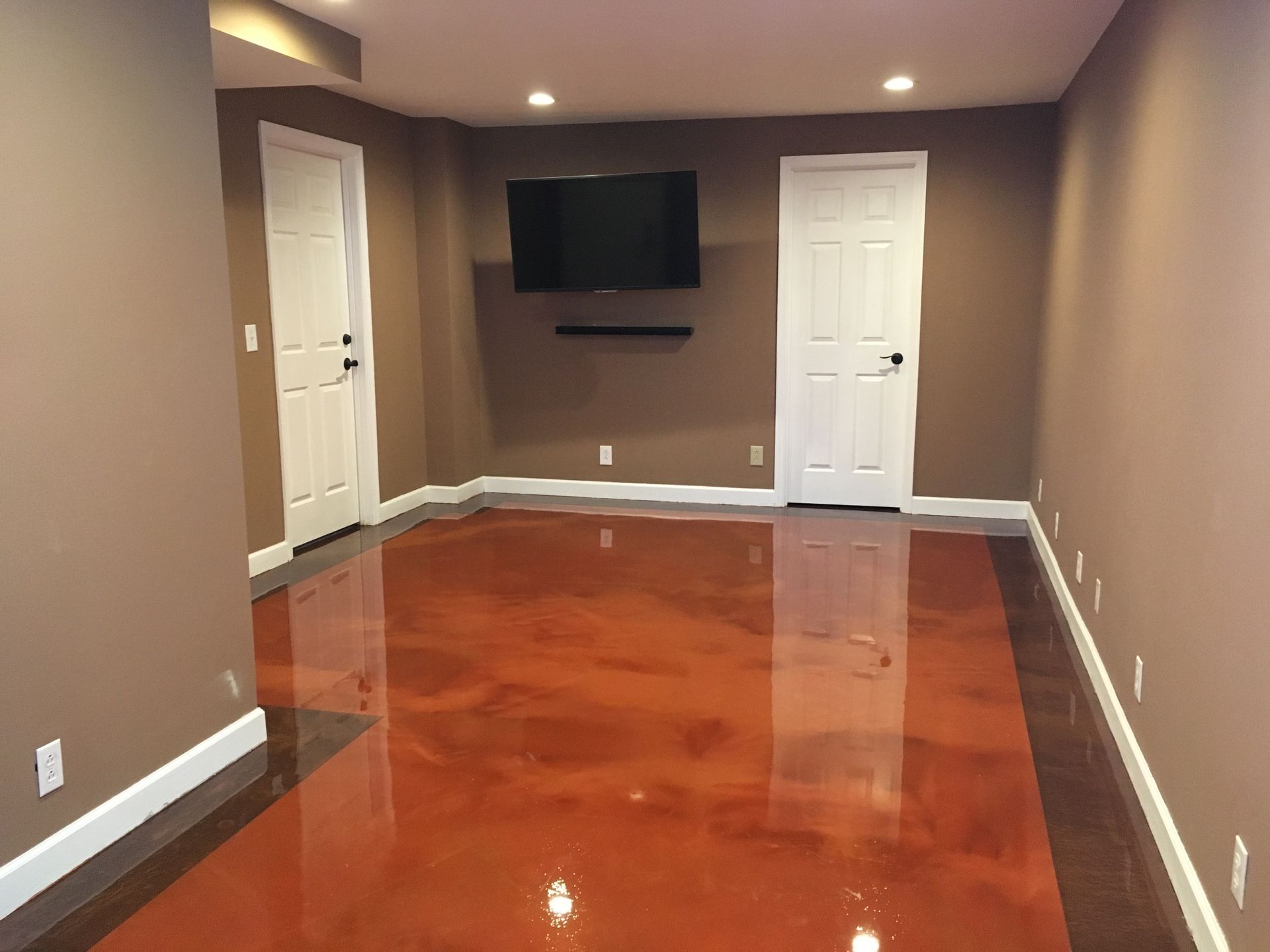 a basement with a red metallic floor and a flat screen tv
