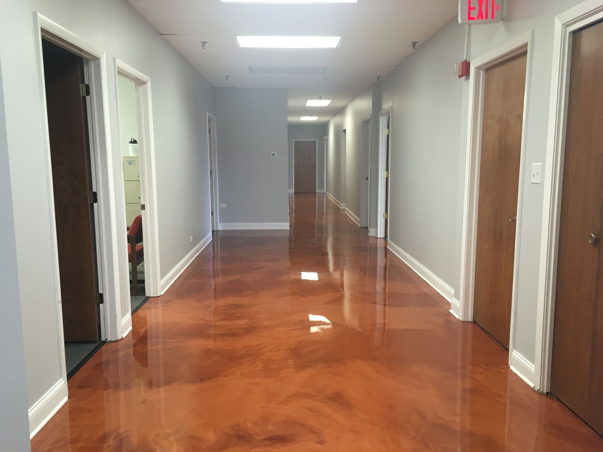 a long hallway with a red exit sign on the wall