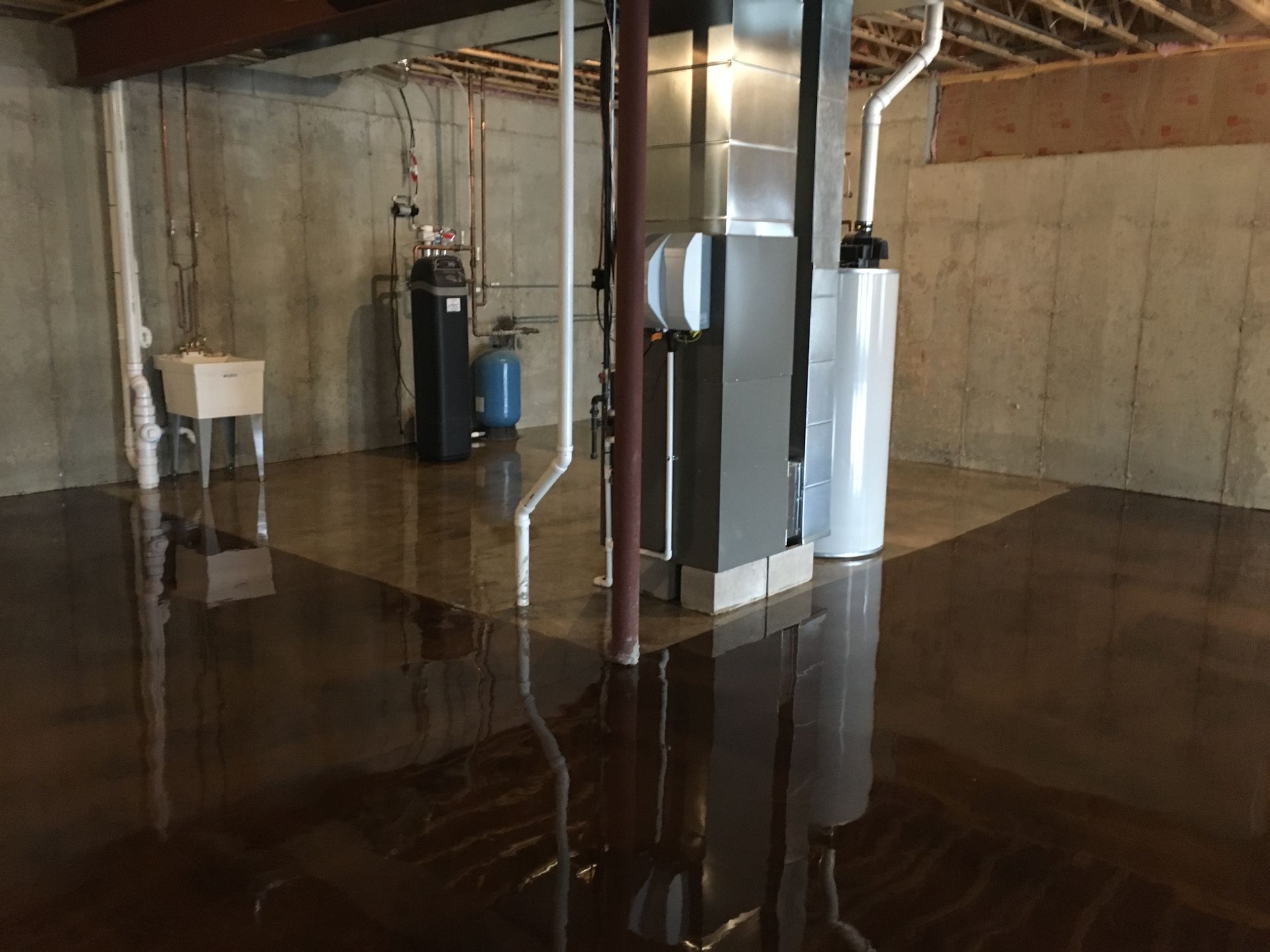 a basement with a sink, heater, and water heater