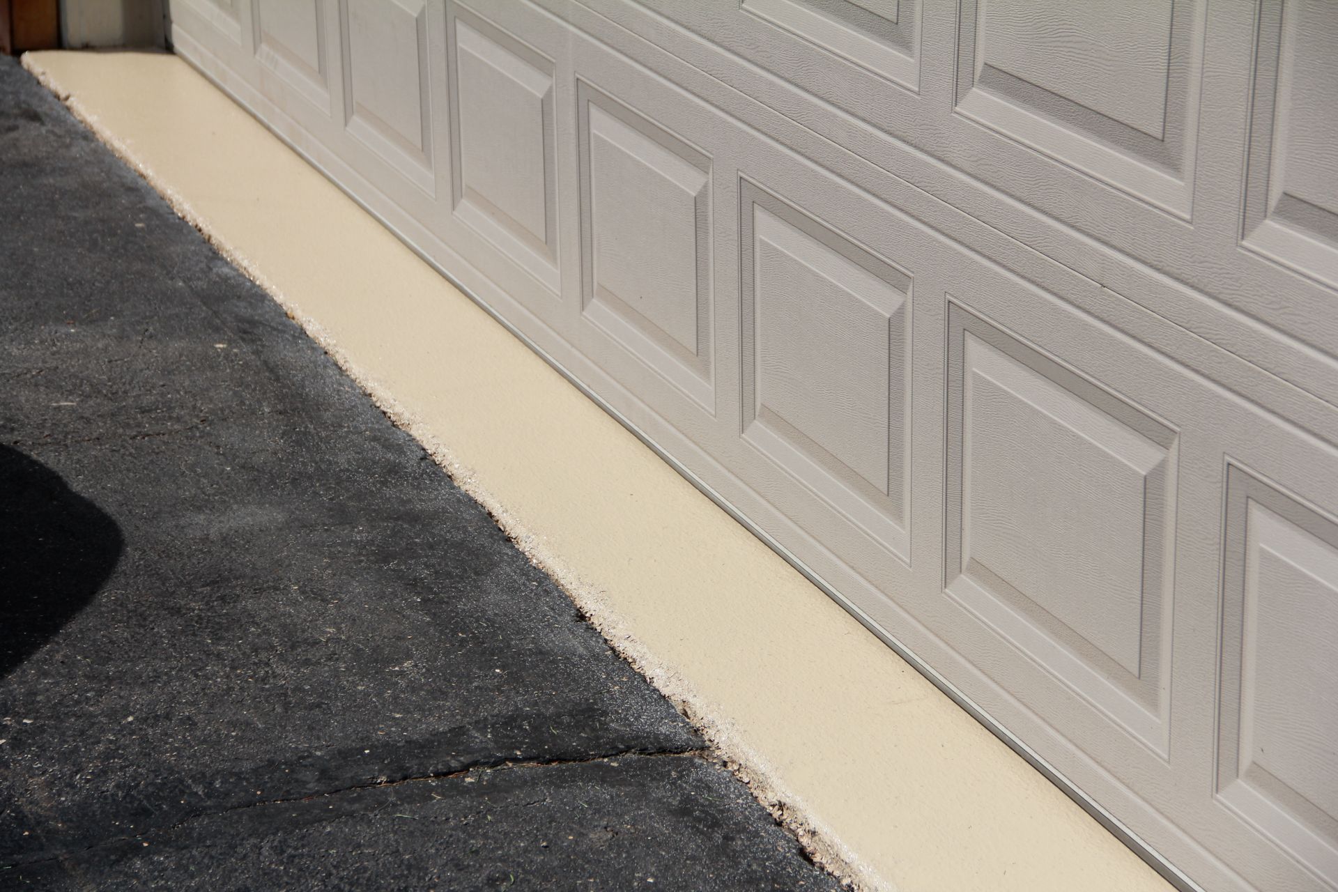 a white garage door is sitting on top of a concrete driveway 