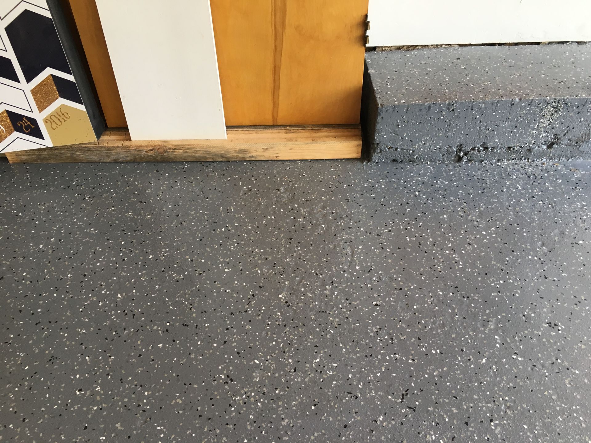 a close up of a gray floor with a wooden door in the background
