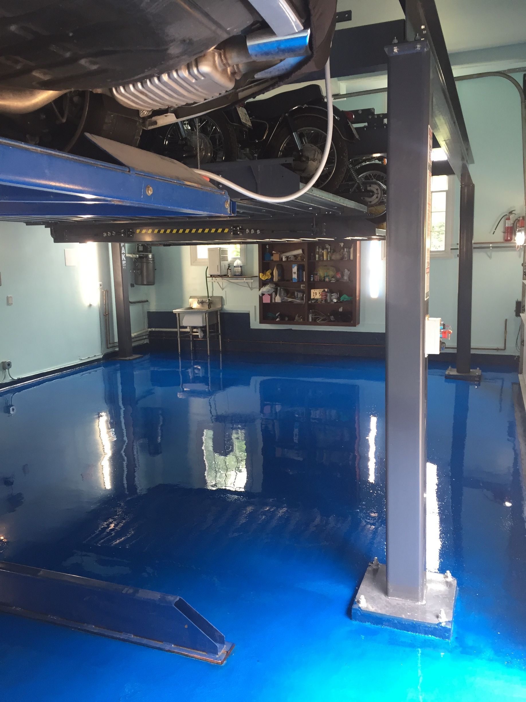 a car is on a lift in a garage with a blue floor