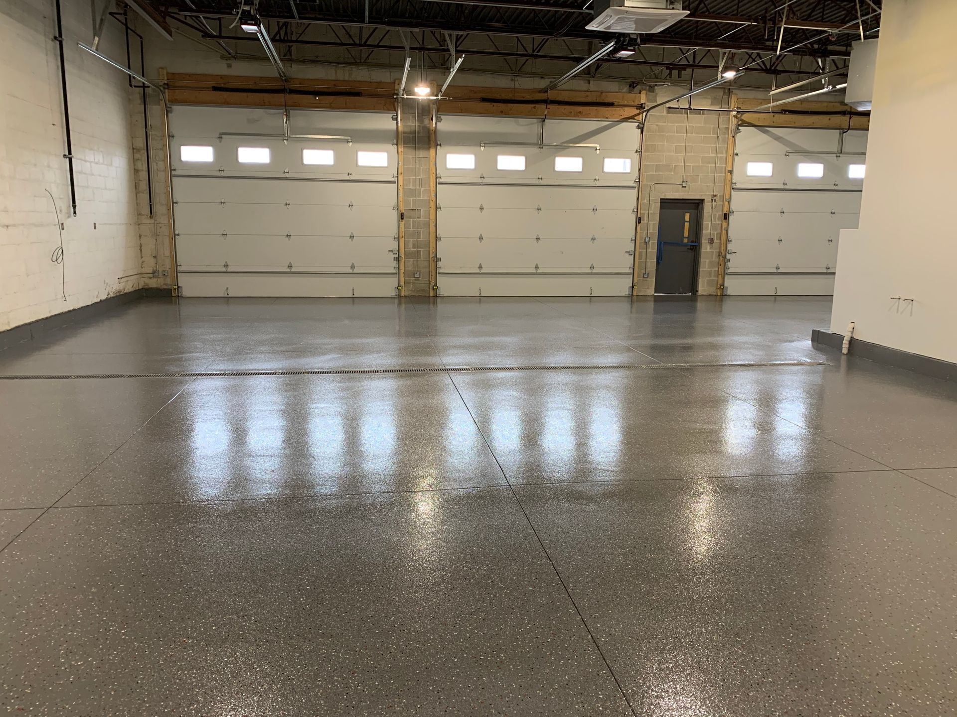 a large empty garage with a gray floor and white garage doors