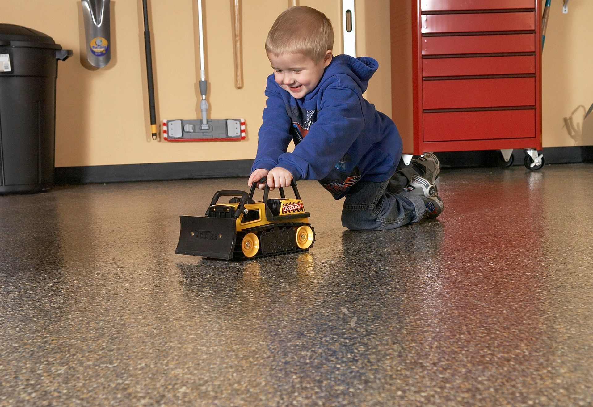 a little boy is playing with a toy bulldozer in a garage