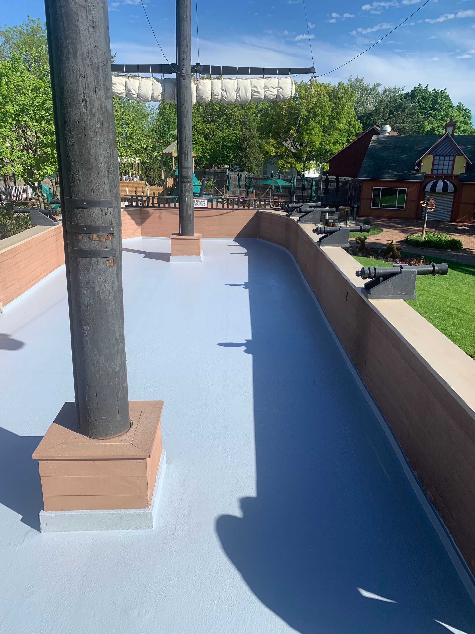 a concrete walkway with a brick wall and trees in the background
