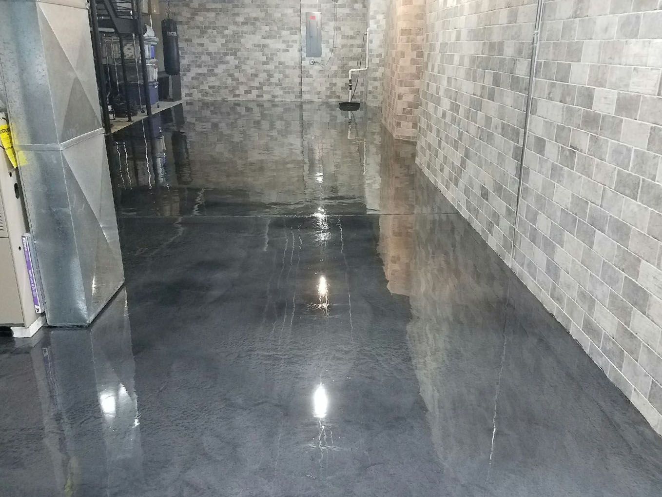 a dark colored concrete floor in a basement with a brick wall