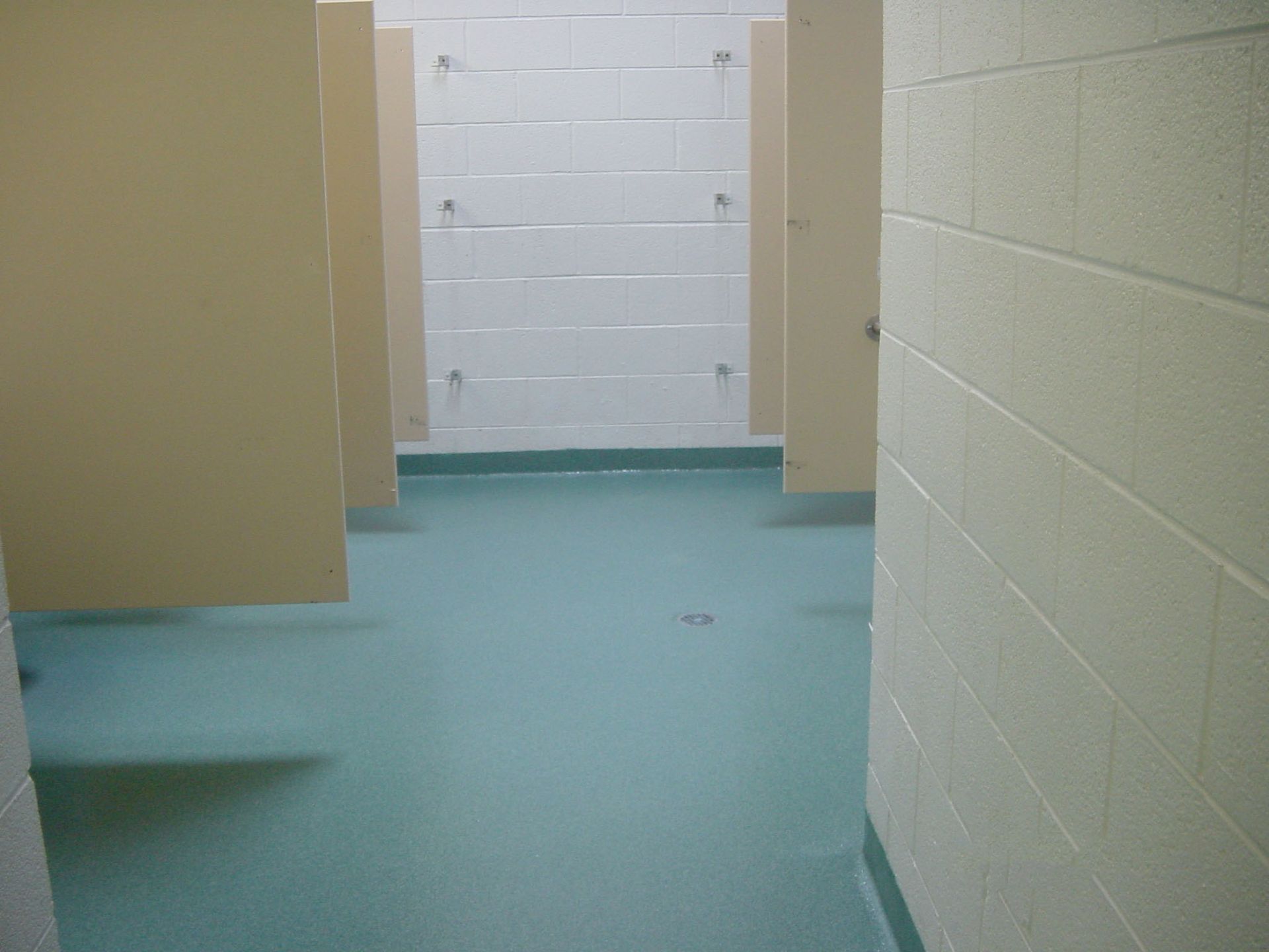 a hallway in a bathroom with a green floor and white walls