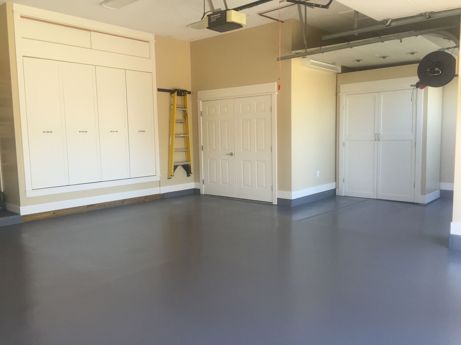 a large empty garage with lots of cabinets and a ladder .