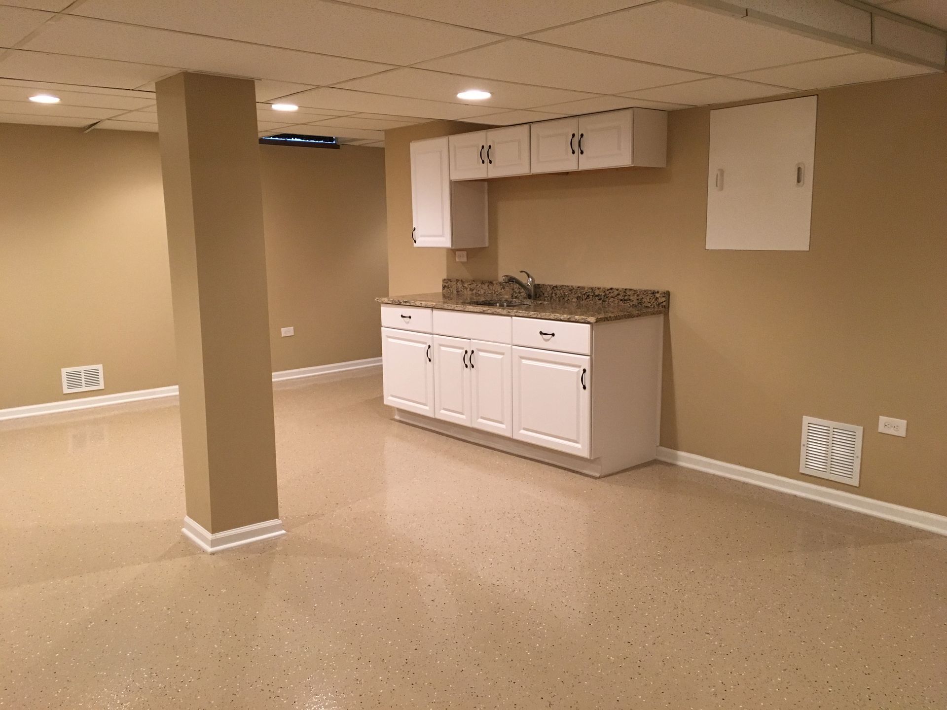 an empty basement with white cabinets and a sink