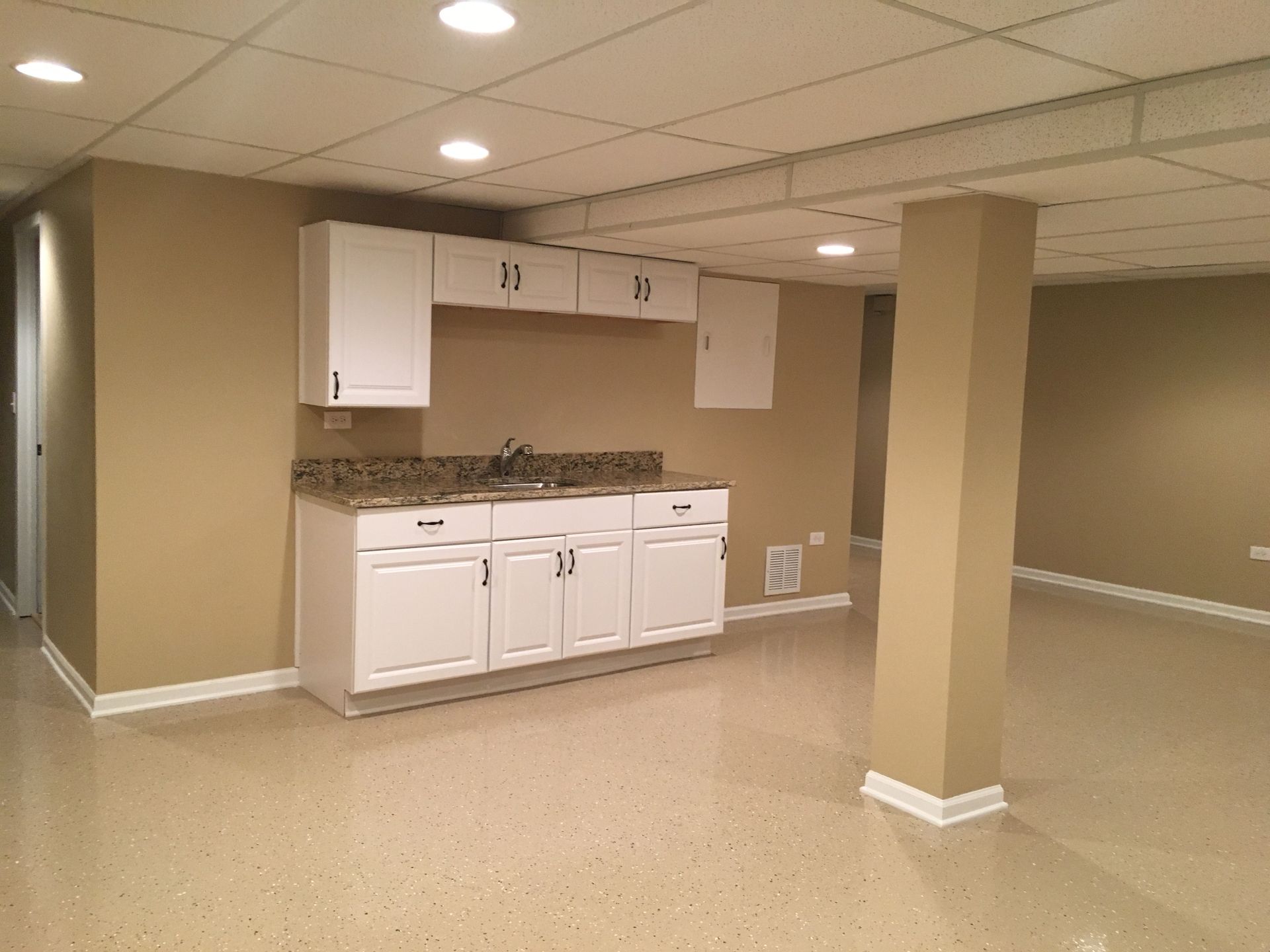 an empty basement with white cabinets and a sink