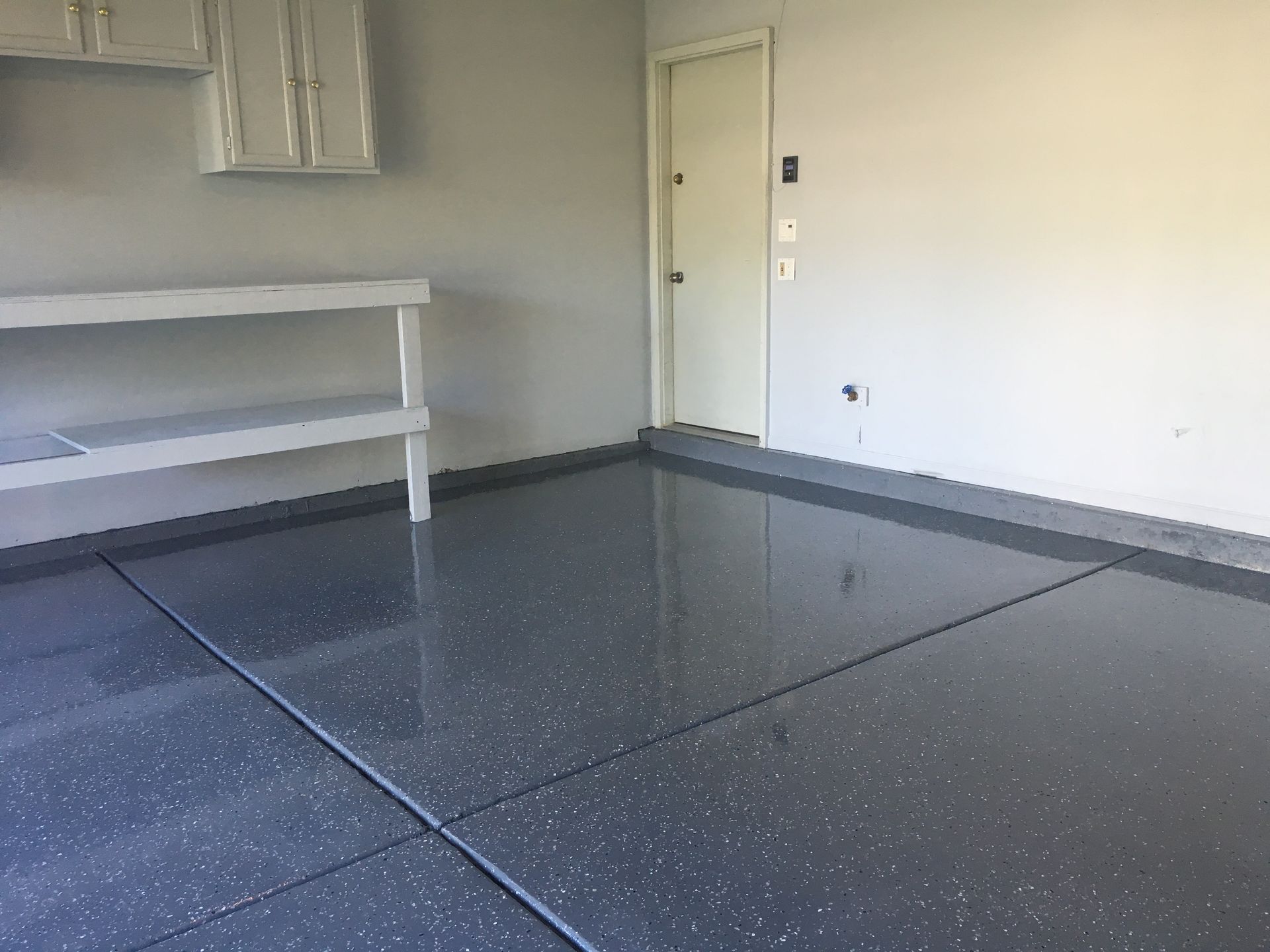 an empty garage with a gray floor and white walls