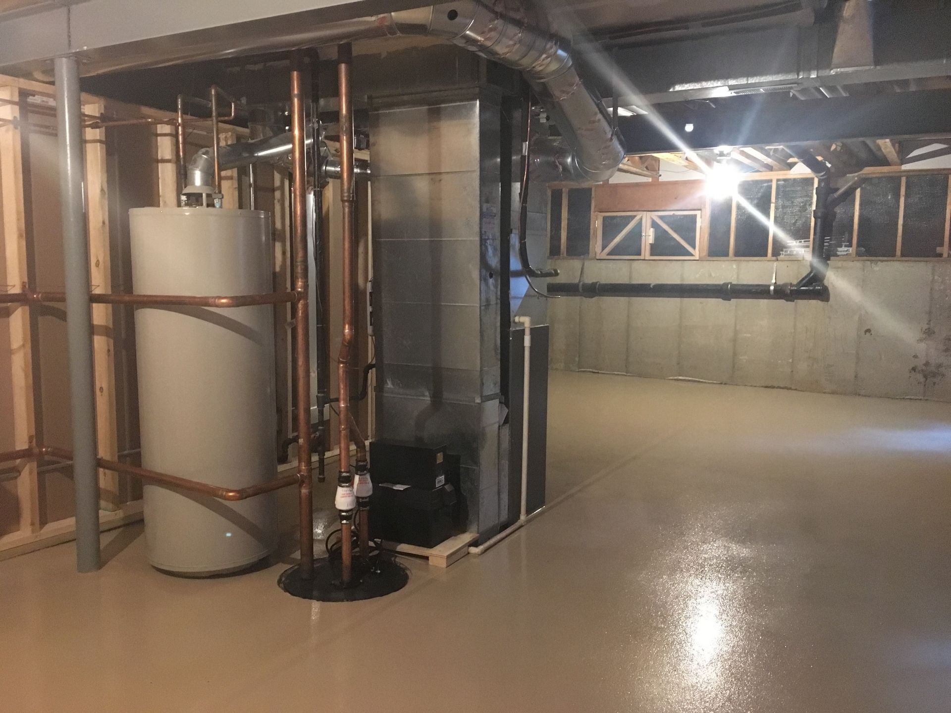 a basement with a water heater and pipes in it