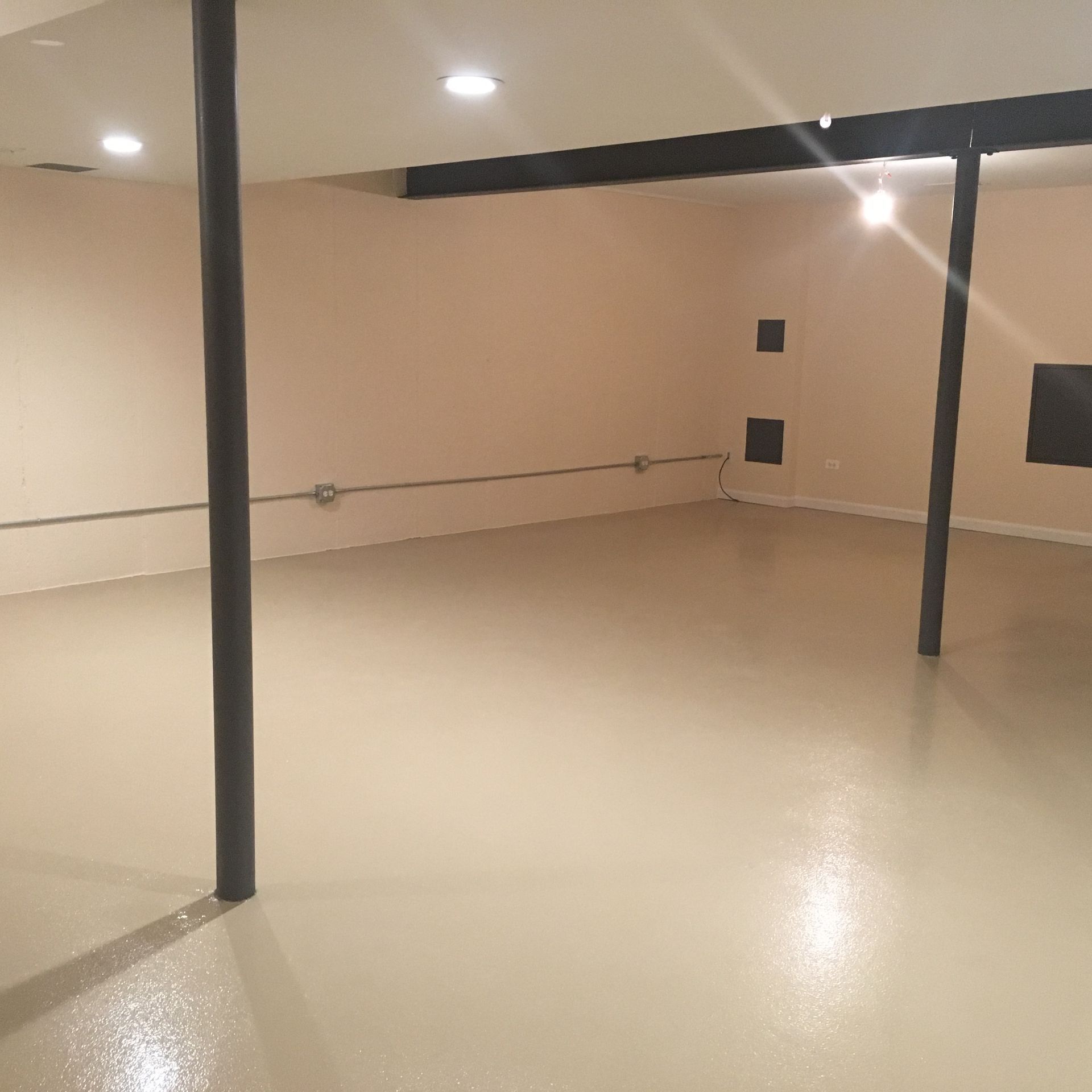 an empty room with a white floor and a black pole