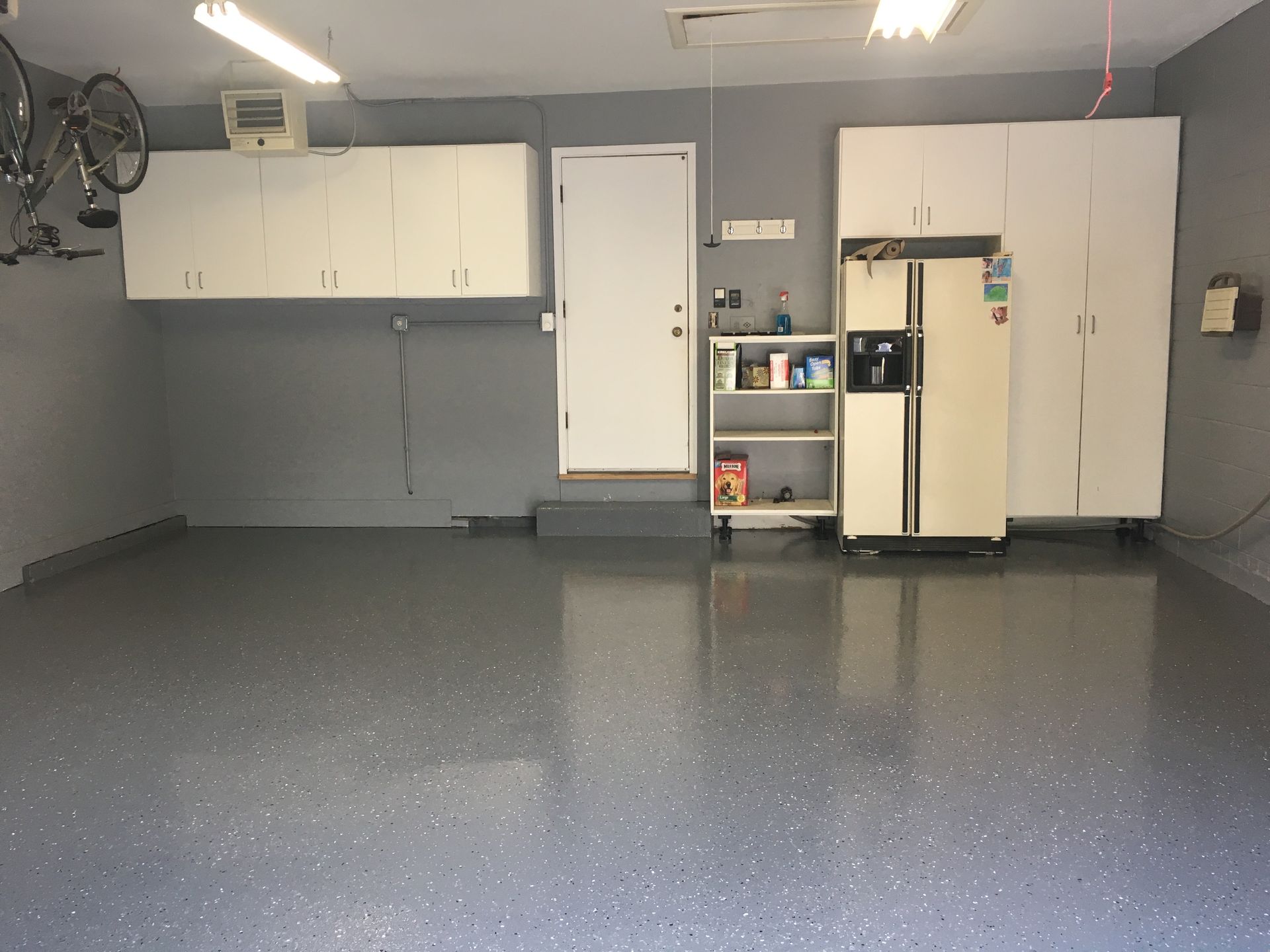 a garage with a refrigerator and a bicycle on the wall