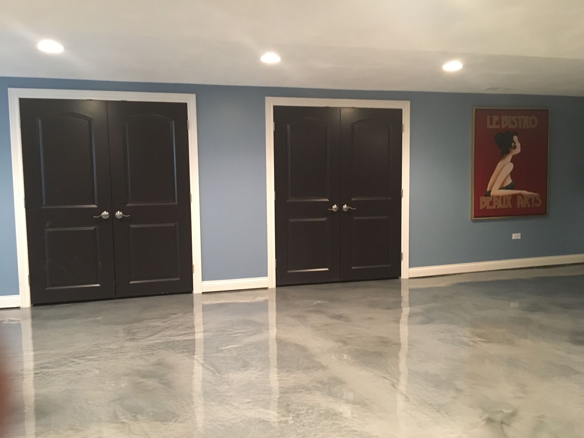 a room with two black doors and a painting on the wall