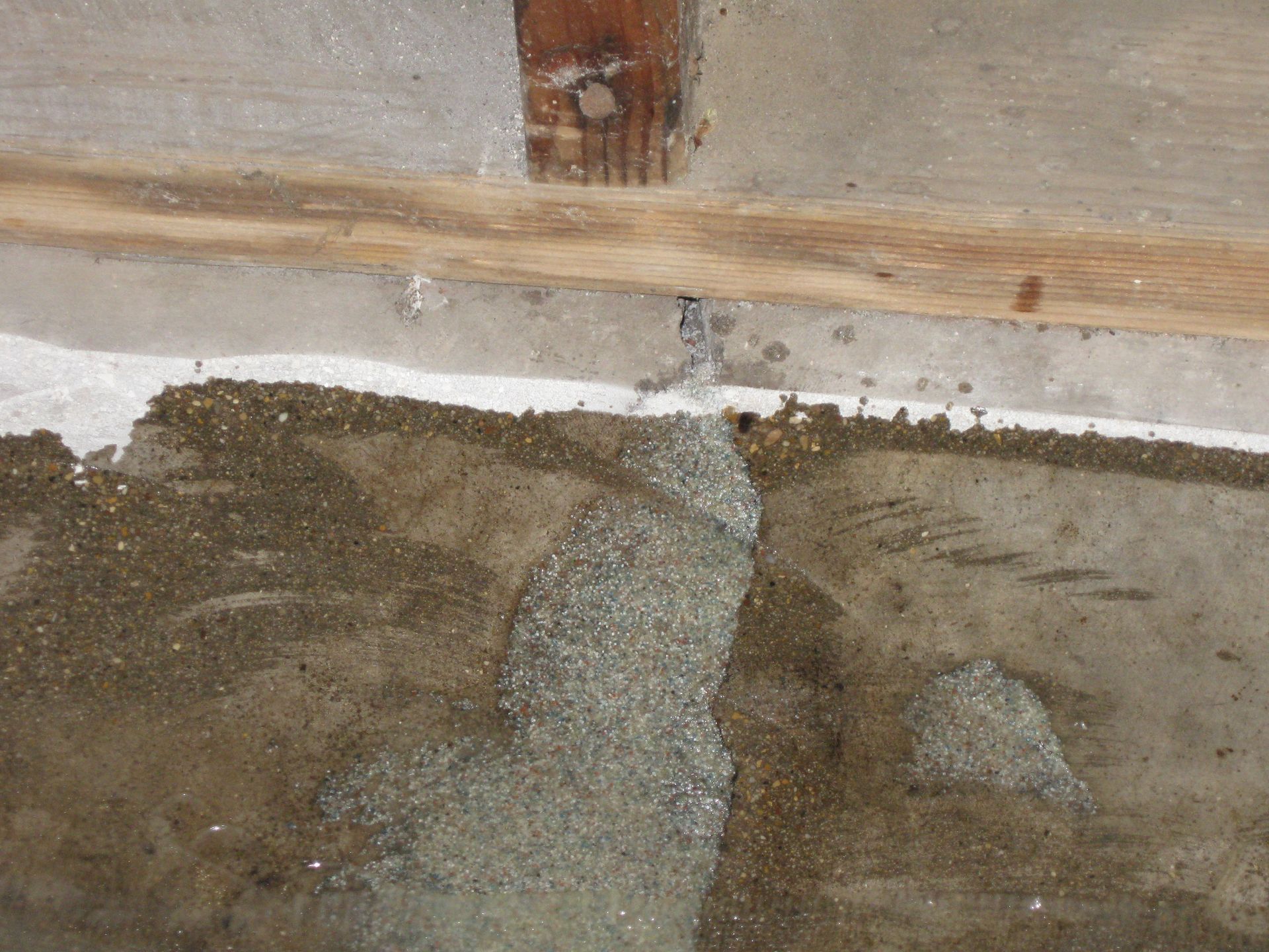 a close up of a concrete floor with a wooden post in the background