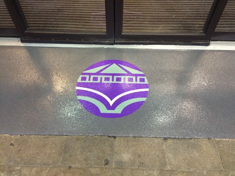 a purple and green logo on a gray surface