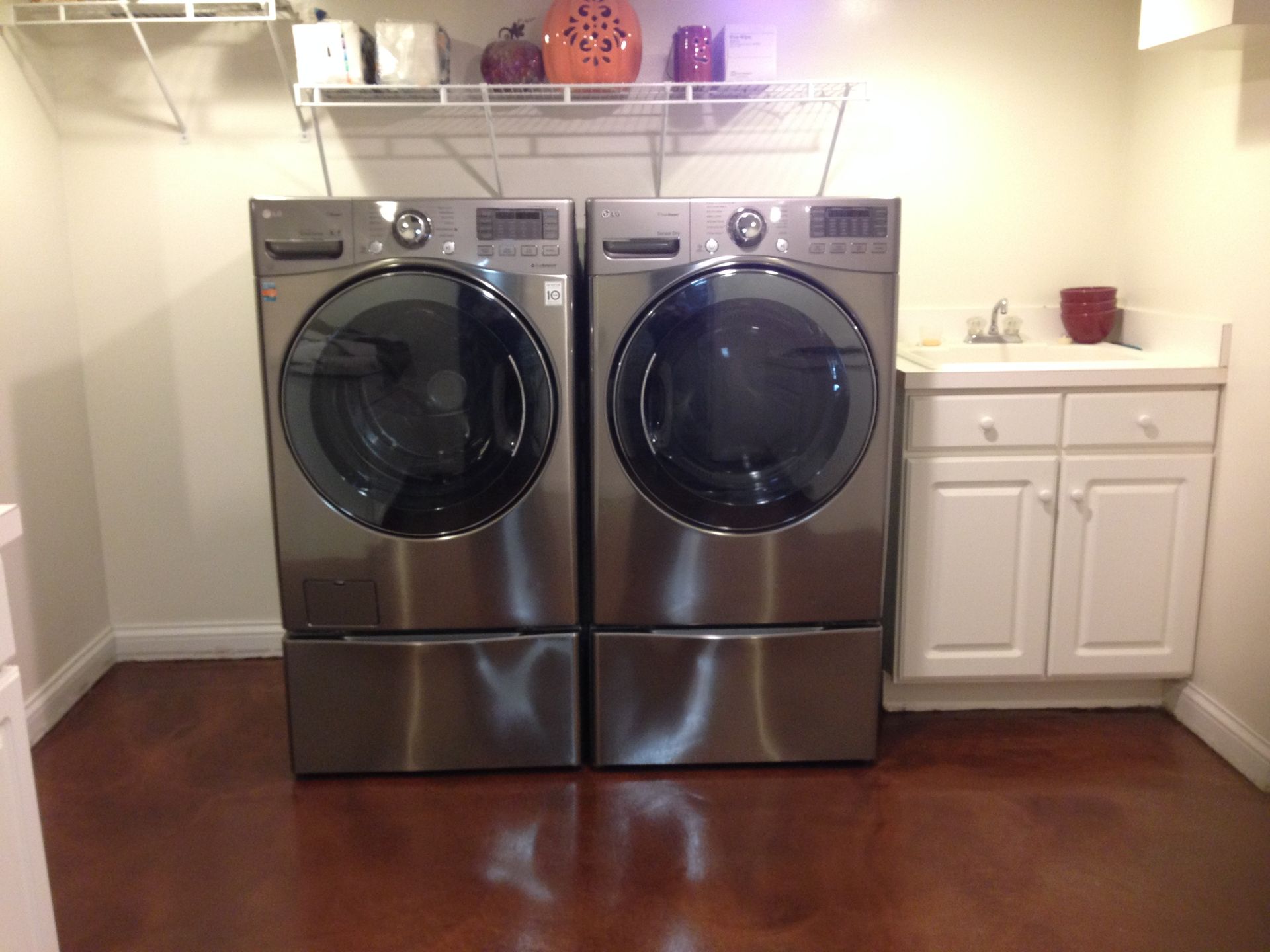 a laundry room with two stainless steel washers and dryers