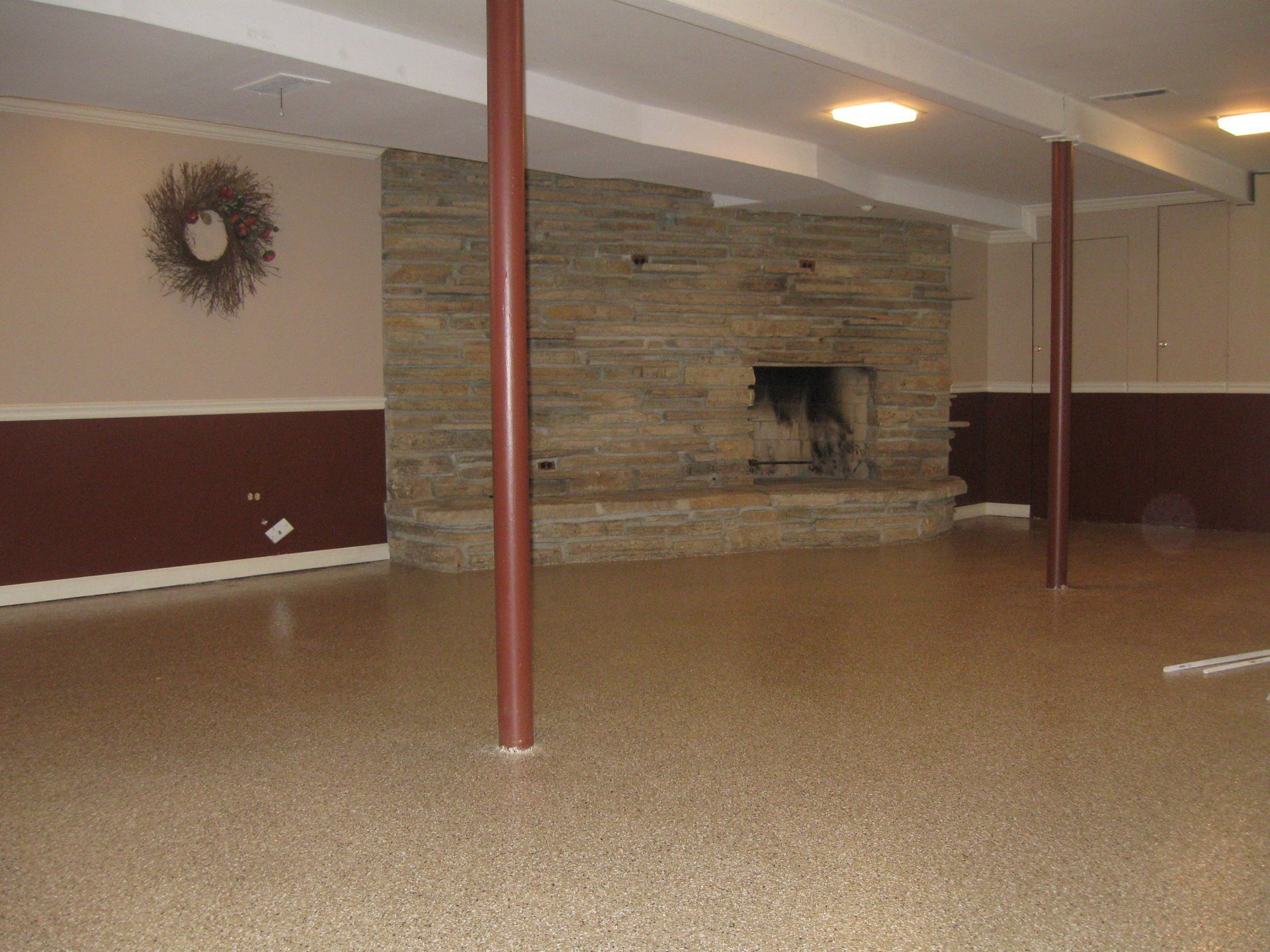an empty basement with a fireplace and a wreath on the wall