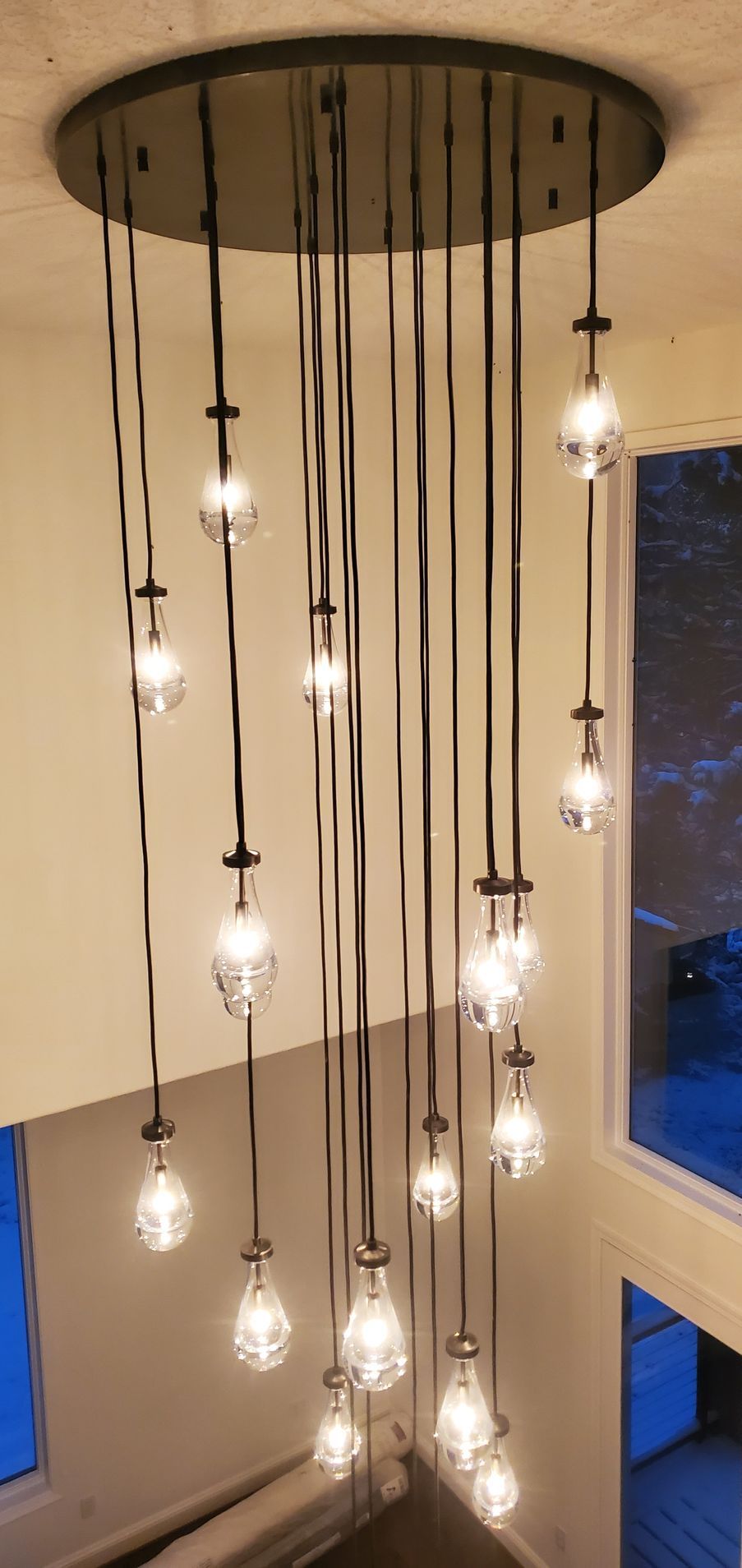 Multi-bulb pendant light fixture in a stairwell. Bulbs are clear glass with dark cords.