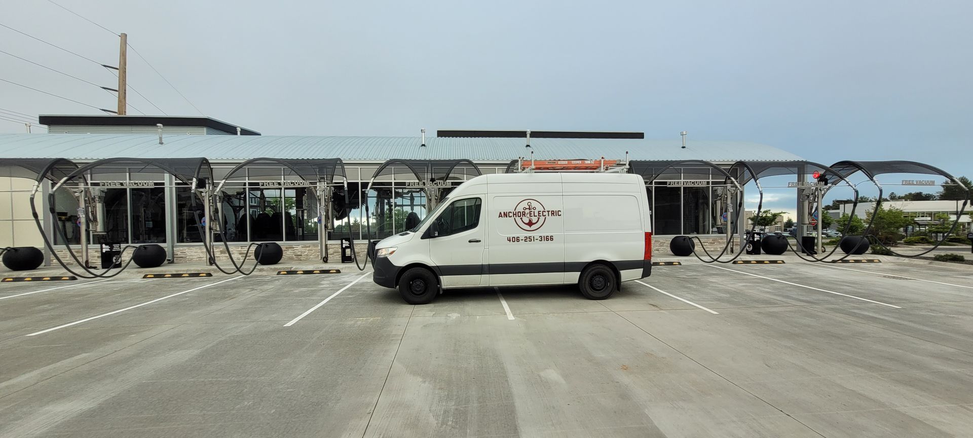 White van parked in a car wash, cloudy sky above.