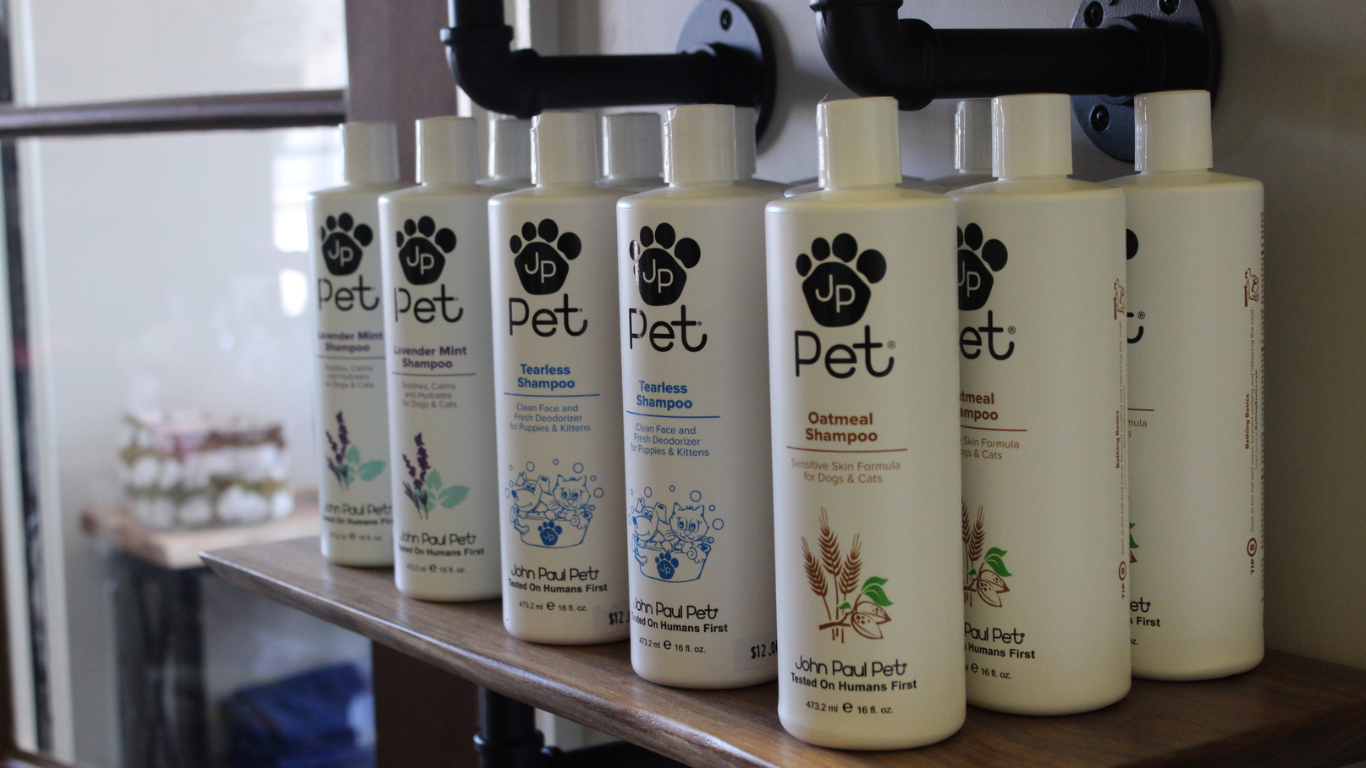 Bottles of pet shampoo are lined up on a wooden shelf.