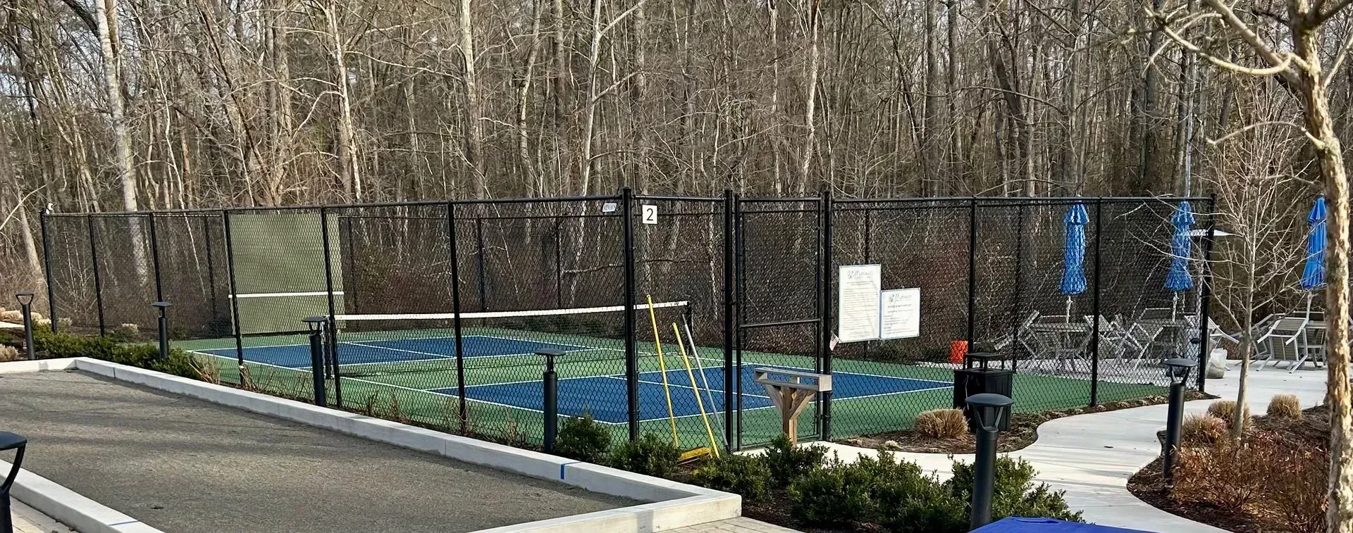 A tennis court with a fence around it and trees in the background.