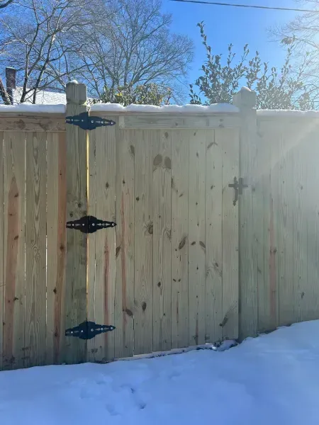 A wooden fence with a gate in the snow.