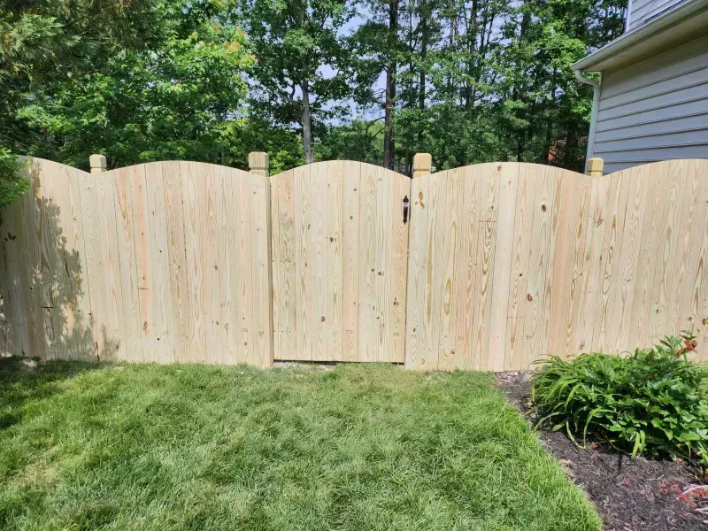 A wooden fence with a gate in the backyard of a house.
