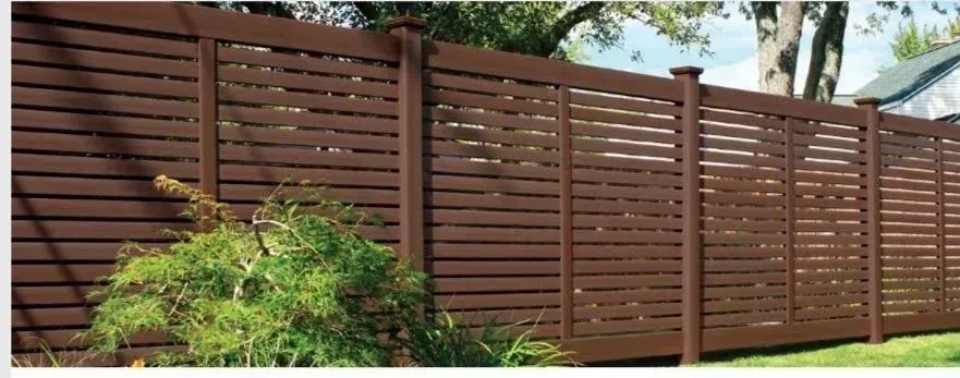 A wooden fence is surrounded by grass and trees