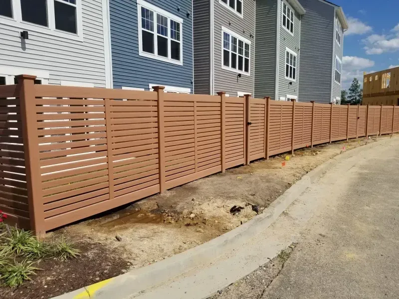 A wooden fence is in front of a row of houses.