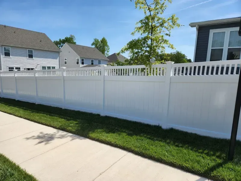 A white fence along a sidewalk next to a house