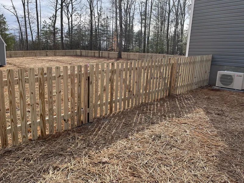 A wooden fence is in the backyard of a house.