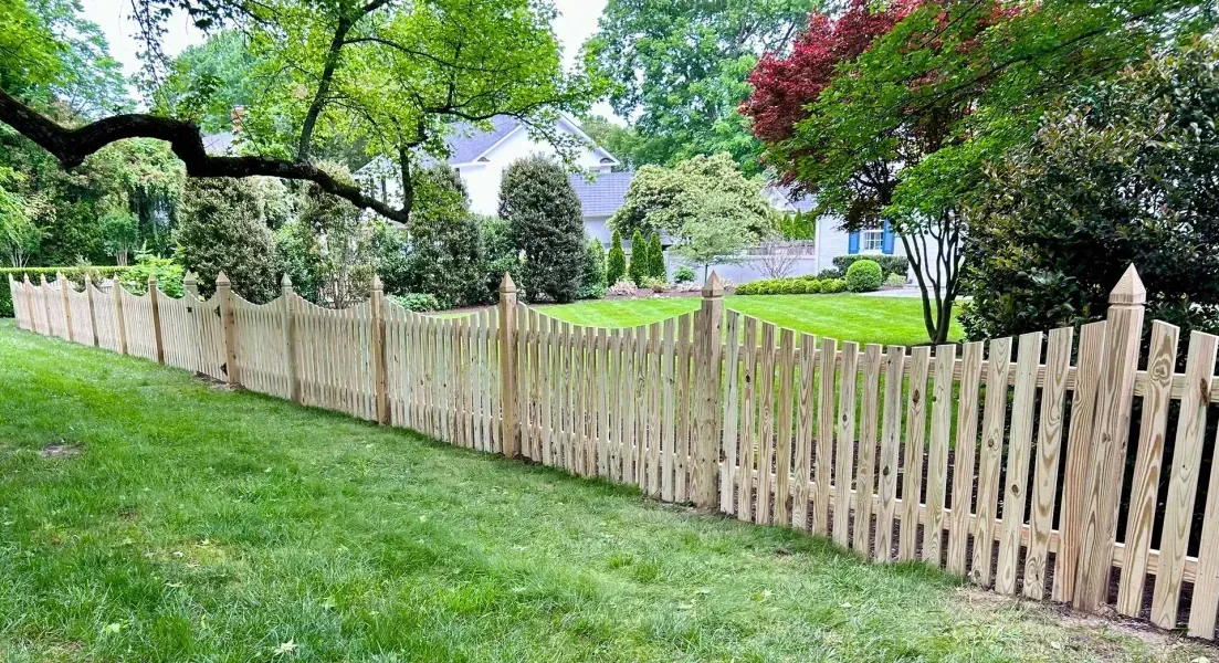 A wooden picket fence surrounds a lush green yard.