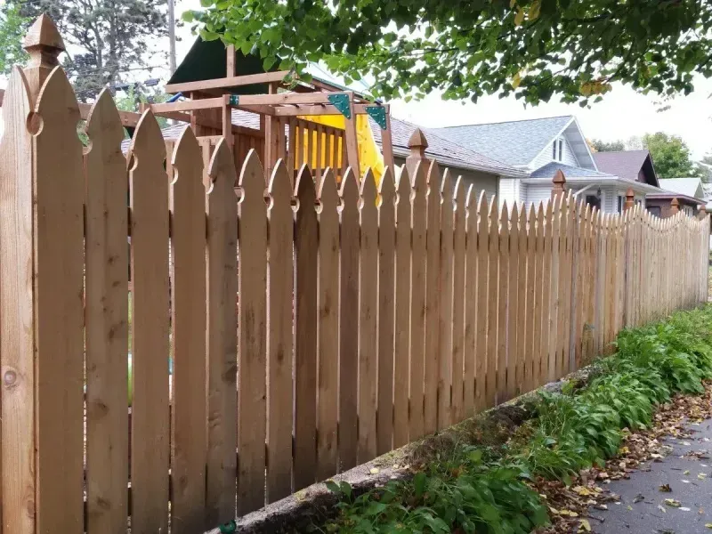 A wooden picket fence with a playground in the background