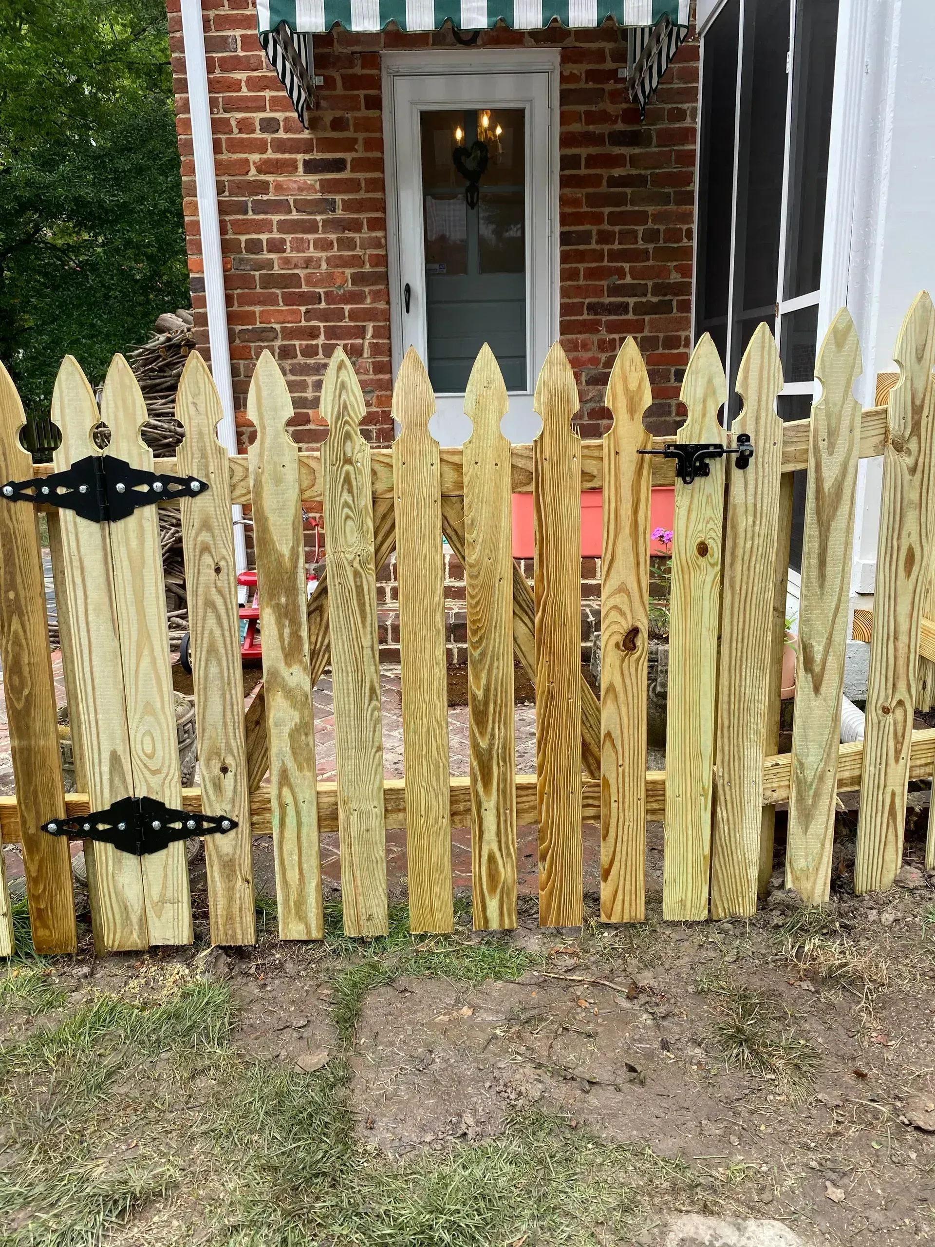 A wooden picket fence is in front of a brick house.