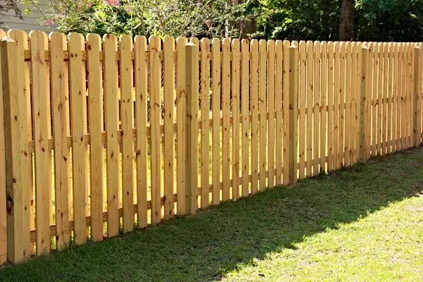 A wooden fence is sitting on top of a lush green lawn.