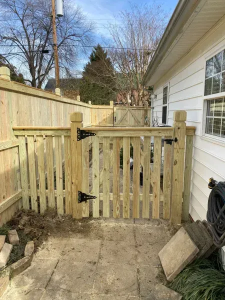 A wooden gate is in the backyard of a house.