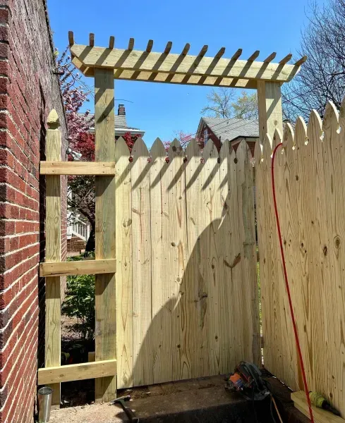 A wooden fence with a pergola on top of it