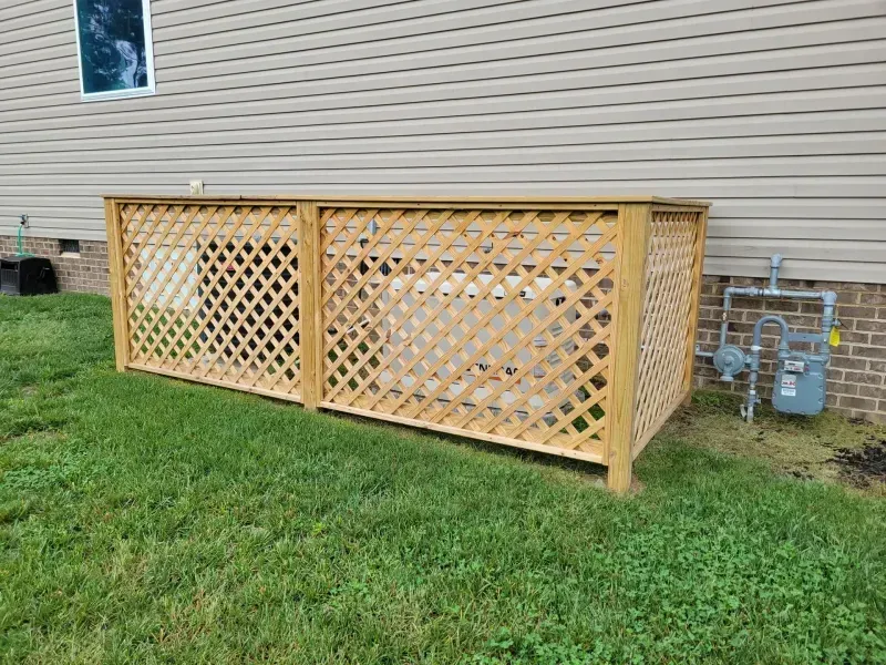 A wooden fence is sitting in the grass next to a house.