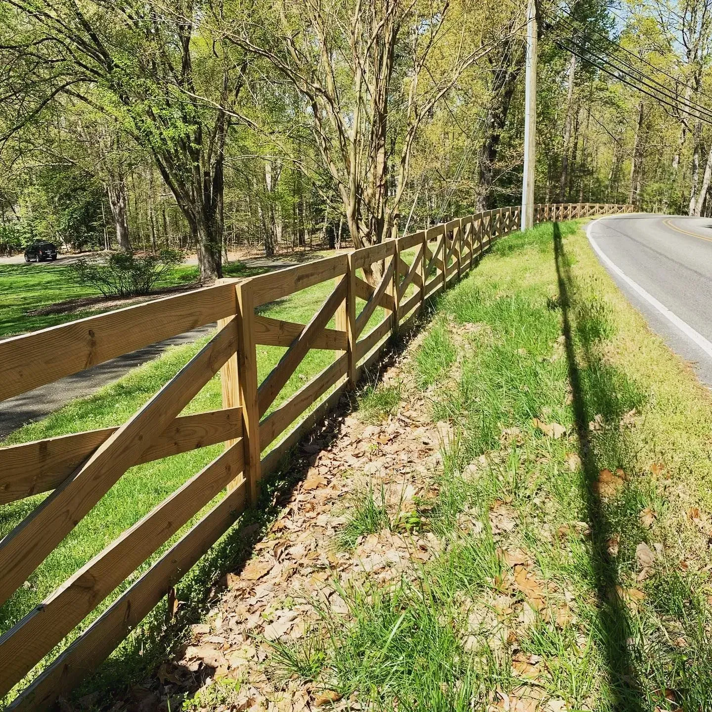 A wooden fence is along the side of a road.