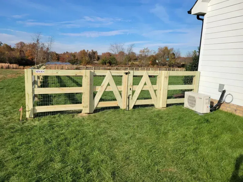 A wooden fence is sitting in the grass in front of a house.