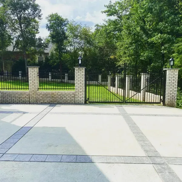 A driveway with a brick wall and a metal gate