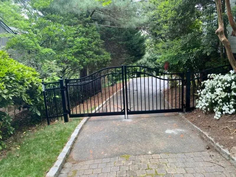 A black gate is sitting on the side of a driveway.