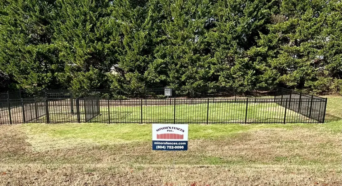 A sign is sitting in the middle of a grassy field next to a fence.