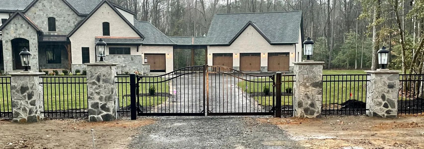 A large house with a stone fence and a gate in front of it.