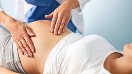 A pregnant woman is being examined by a doctor.